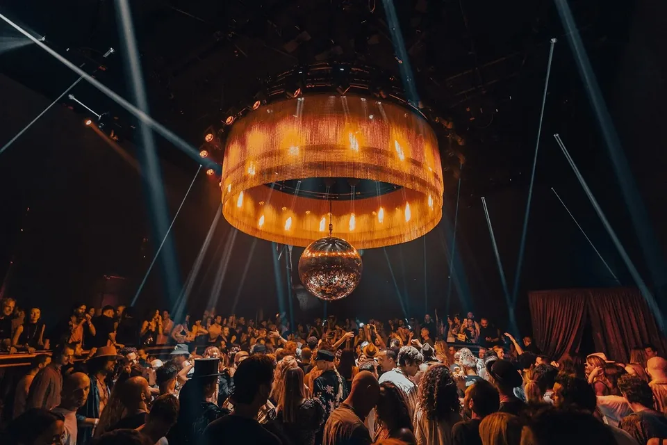 Pista de Club Chinois con público, haces de luz y una estructura circular iluminada sobre la sala.