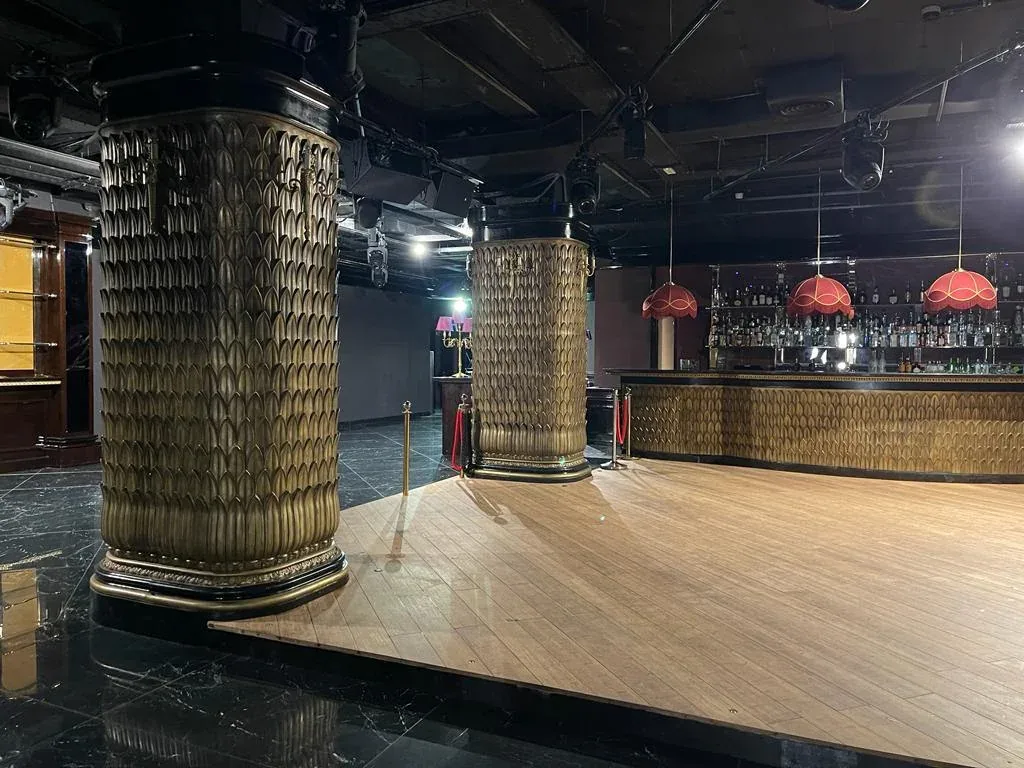 Sala de Club Chinois con columnas de acabado dorado, una zona de pavimento claro y barra al fondo.