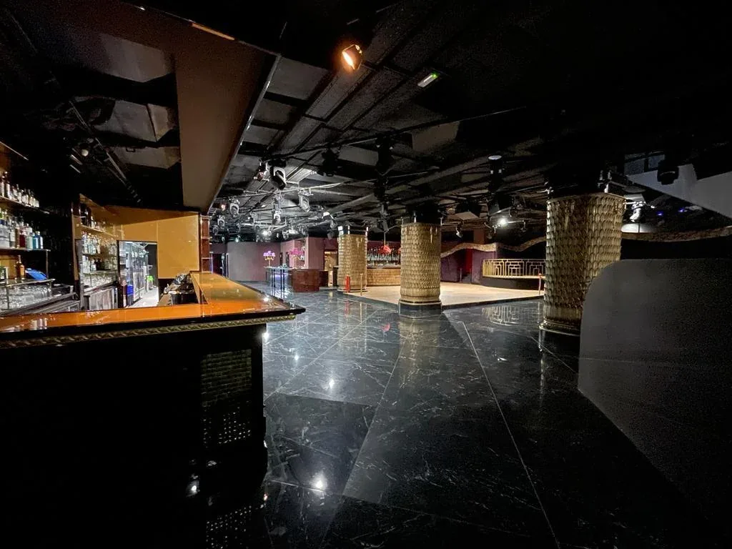 Vista general del interior de Club Chinois con barras, columnas decoradas y pavimento oscuro.