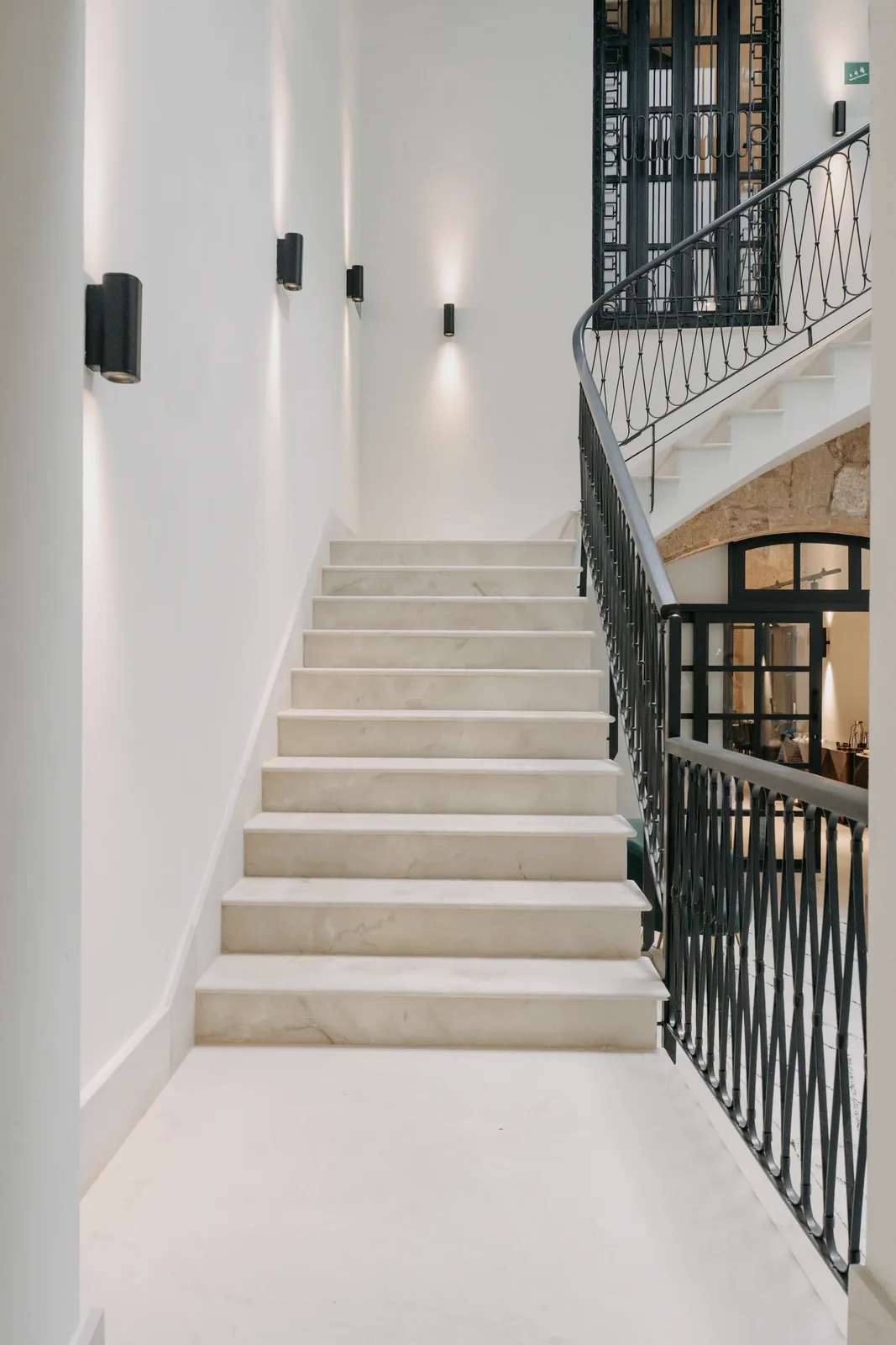 Escalera de CONVENDUM Palma con peldaños claros, paredes blancas y barandilla oscura.