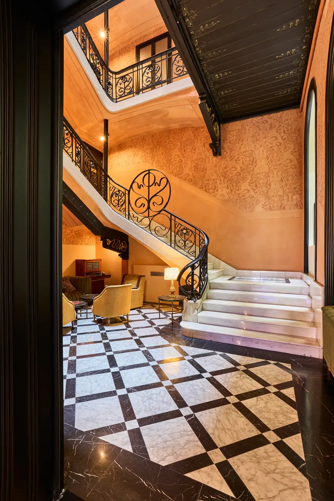 Escalera del Hotel España Ocean Drive con peldaños claros, barandillas ornamentadas y un distribuidor de pavimento geométrico.