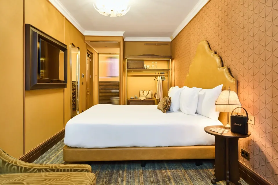 Habitación del Hotel España Ocean Drive con cama, paredes amarillas, televisión y armario abierto al fondo.