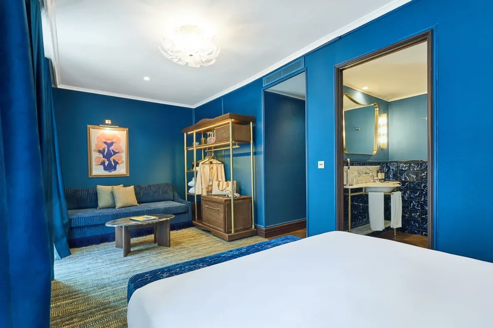 Habitación del Hotel España Ocean Drive con paredes azules, zona de estar, armario abierto y acceso al baño.