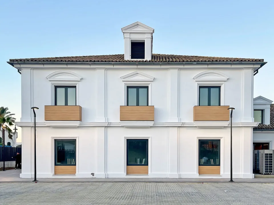 Fachada blanca de ILERNA Jerez con ventanas, balcones de tono madera y una pequeña buhardilla.