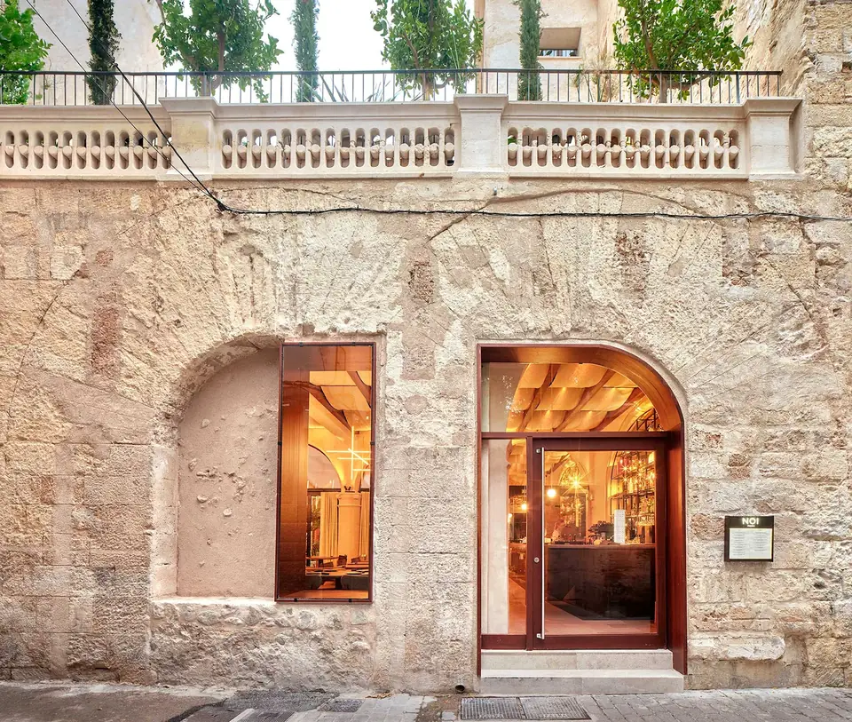 Entrada de Nobis Hotel Palma con puerta y ventana bajo arcos, sobre una fachada de textura irregular.