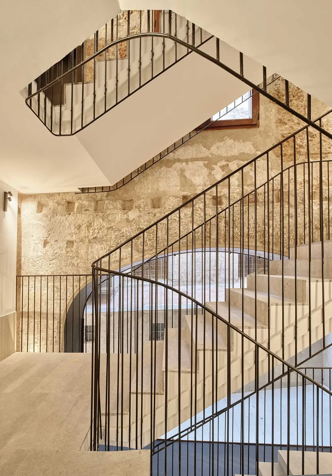 Escalera de Nobis Hotel Palma con tramos superpuestos, peldaños claros y barandillas oscuras.