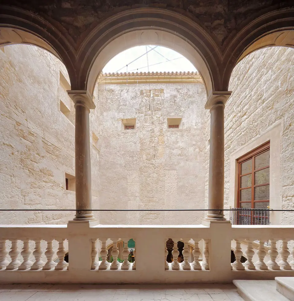Galería de Nobis Hotel Palma con columnas, arcos y una balaustrada frente a los muros del patio.