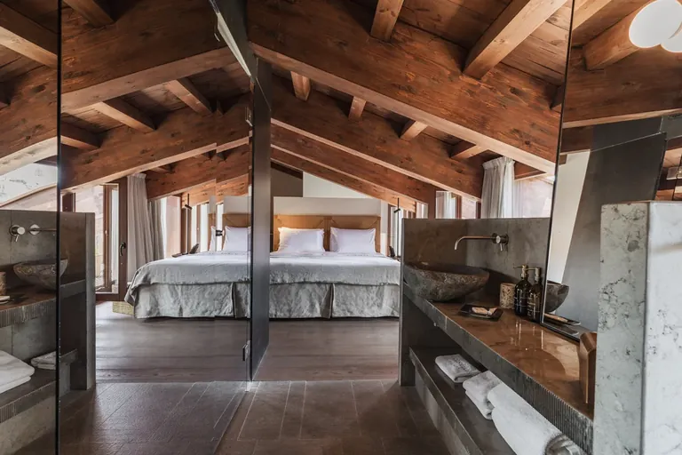 Habitación de Nobis Hotel Palma bajo una cubierta inclinada de vigas vistas, con cama y bañera.