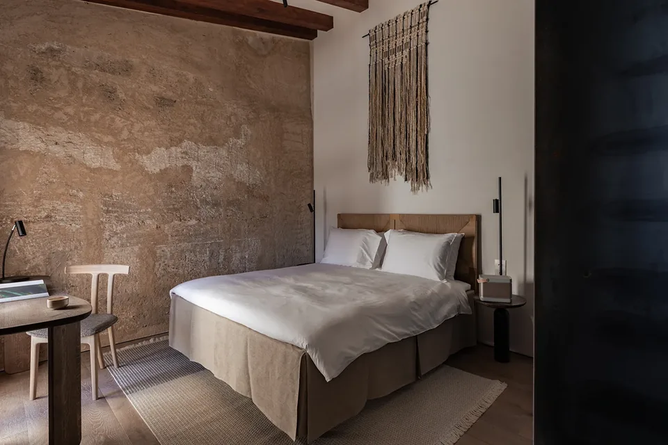 Habitación de Nobis Hotel Palma con cama doble, pared de textura irregular y vigas en el techo.