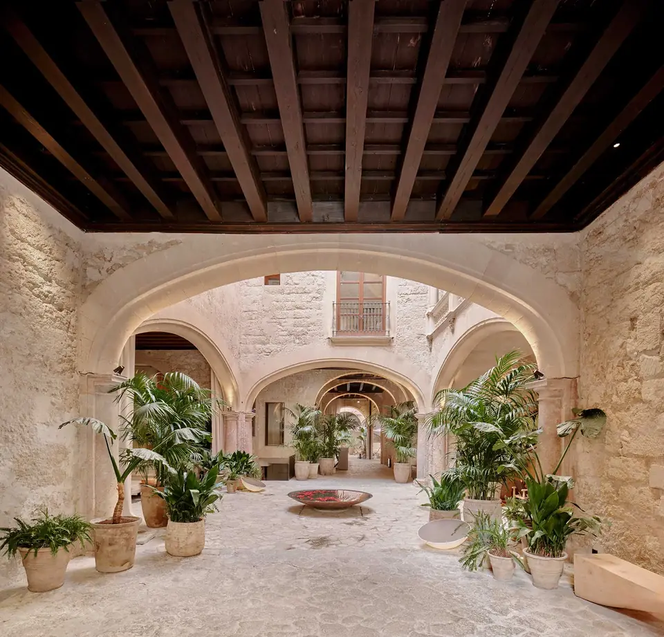 Patio de Nobis Hotel Palma con arcos, columnas y plantas bajo un techo de vigas oscuras.