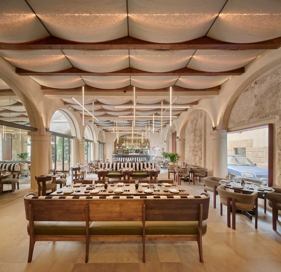 Restaurante de Nobis Hotel Palma con mesas preparadas, bancos y un techo de superficies curvas.