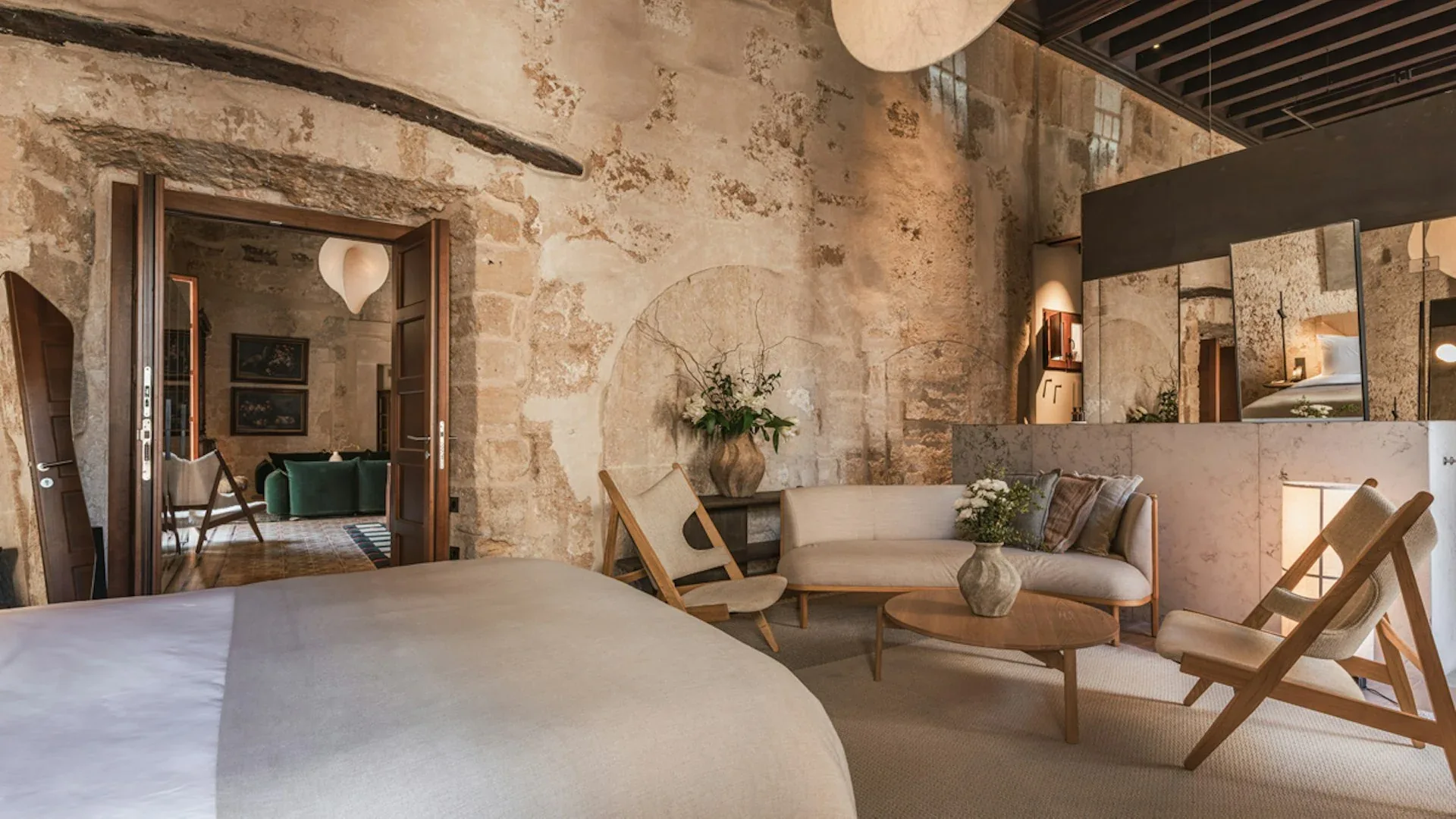 Salón de Nobis Hotel Palma con sofá, sillones, mesa baja y un espejo junto a una puerta abierta.