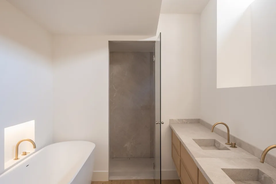 Baño de la Carrer Sol en Palma con bañera, dos lavabos y una ducha bajo la luz de un hueco superior.