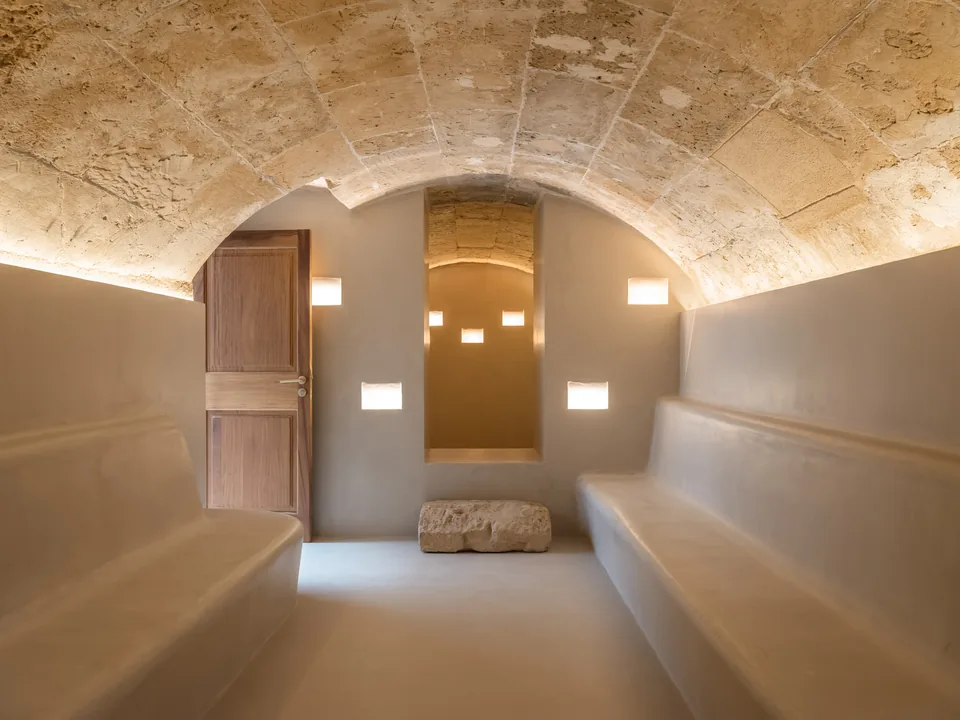 Sala de la Carrer Sol en Palma con bóveda de textura irregular, bancos laterales y pequeños huecos iluminados al fondo.