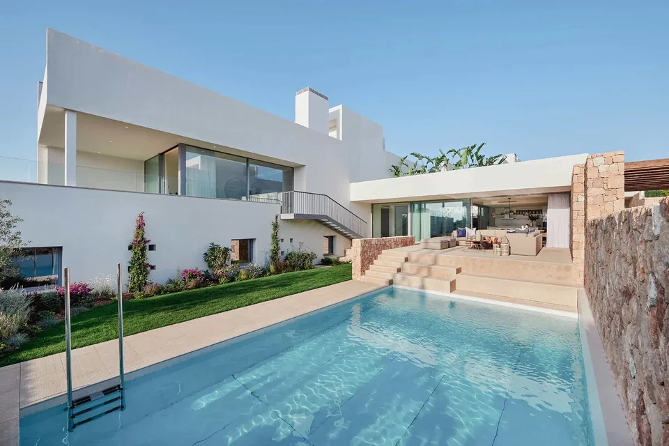Exterior de TWA Cala Comte en Ibiza con fachada blanca, grandes ventanales, terraza y piscina.